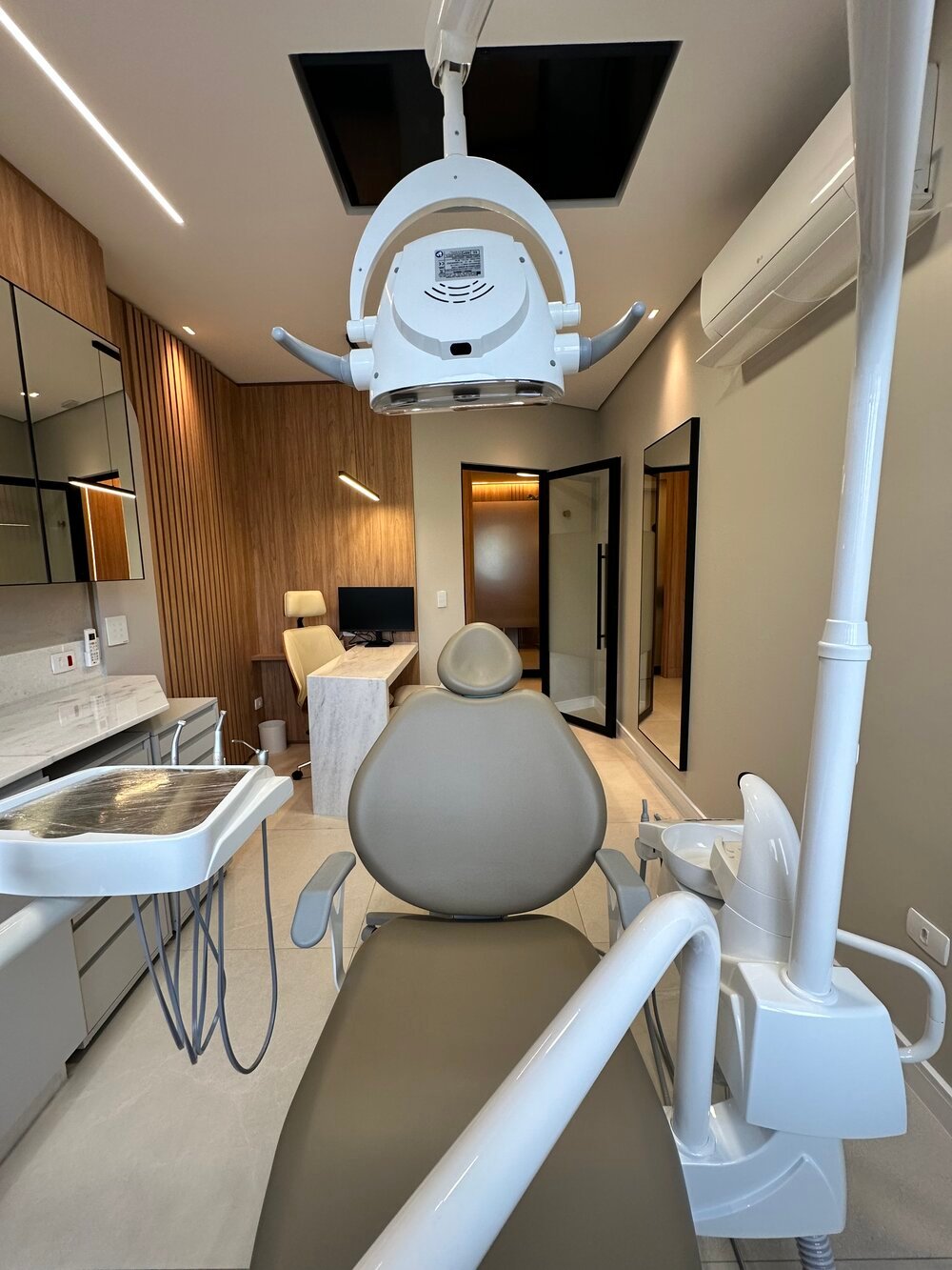 Consultório com cadeira odontológica e sala de reuniões ao fundo